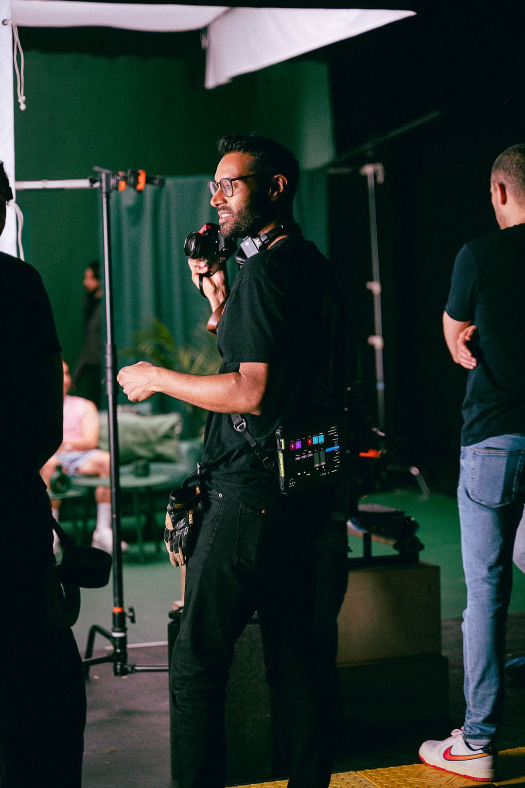 Crew member holding headphones beside the studio set